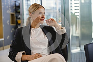 Pretty stylish businesswoman sitting in modern office and looks away during working day