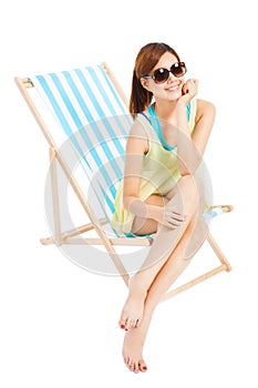 Pretty sunshine girl smiling and sitting on a beach chair