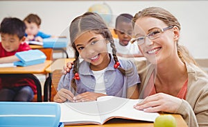 Pretty teacher helping pupil in classroom