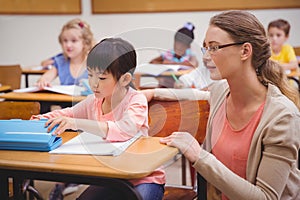 Pretty teacher helping pupil in classroom