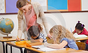 Pretty teacher helping pupil in classroom