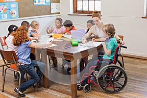 Pretty teacher helping pupils in classroom