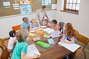 Pretty teacher helping pupils in classroom