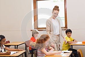 Pretty teacher helping pupils in classroom