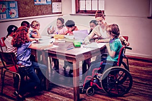 Pretty teacher helping pupils in classroom