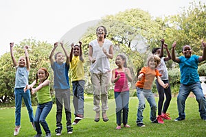 Pretty teacher jumping with pupils outside