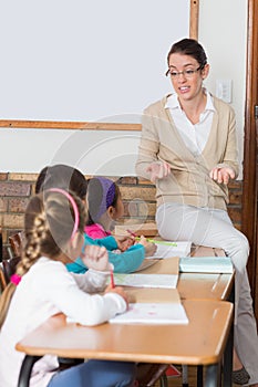 Pretty teacher talking to the young pupils in classroom