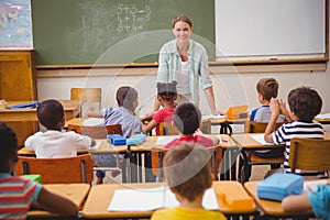 Pretty teacher talking to the young pupils in classroom