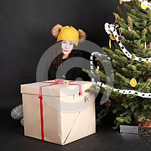 Pretty teen girl behind gift by Christmas tree