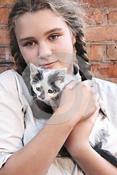 Pretty teen girl is holding a small kitten