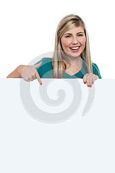 Pretty teen girl indicating downwards over ad board photo