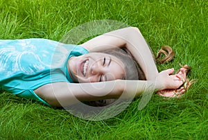 Pretty teen girl lying on the grass. laughter, joy, positive emotions