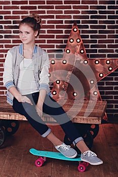 Pretty teen girl with skateboard in studio