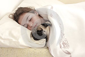 Pretty teen girl sleeps hugging a pug dog in bed