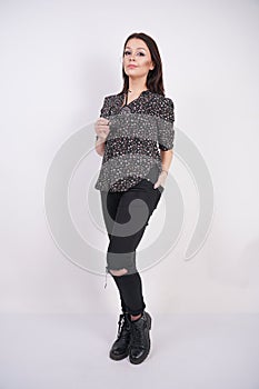 Pretty teen girl wearing fashion casual shirt and black torn jeans posing with eyeglasses on white studio background