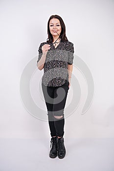 Pretty teen girl wearing fashion casual shirt and black torn jeans posing with eyeglasses on white studio background