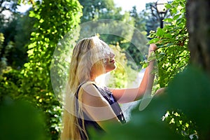 Pretty teenage girl 14-16 year old with curly long blonde hair in beautiful adult dress in the green park in a summer day outdoors