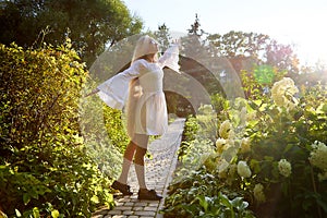 Pretty teenage girl 14-16 year old with curly long blonde hair dancing in the green park in a summer day outdoors. Beautiful