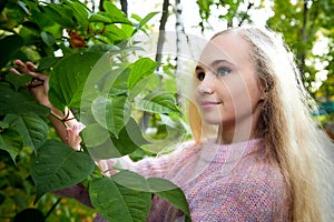 Pretty teenage girl 14-16 year old with curly long blonde hair in the green park in a summer day outdoors. Beautiful portrait