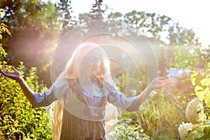 Pretty teenage girl 14-16 year old with curly long blonde hair in the green park in a summer day outdoors. Beautiful portrait