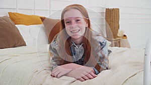 Pretty teenage girl with freckles smiling at bedroom