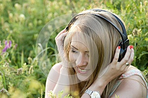 Pretty teenage girl with headphones on the grass