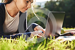 Pretty teenage girl laying on a grass at the park