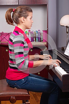 Pretty teenage girl playing on piano