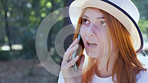 Pretty teenage girl with red hair speaking on mobile phone outdoors.