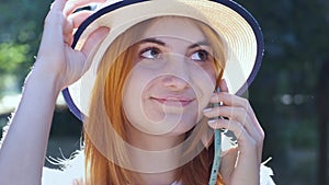 Pretty teenage girl with red hair speaking on mobile phone outdoors.