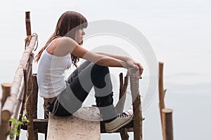 Pretty teenage girl sitting on the dock beside the river on beau