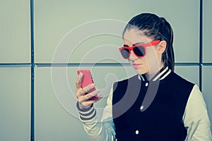 Pretty teenage girl in sunglasses using her smart phone