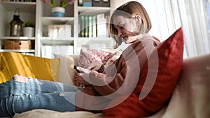 Pretty teenage girl using a smart phone sitting on a couch at home. Teen browsing the Internet on her phone. Teenagers addiction t