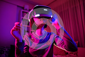 Pretty teenage girl wearing virtual reality headset in a dark room. Cute teen using VR glasses to play a game. Child in virtual