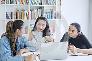 Pretty teenage girls studying together in the library