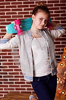 Pretty teenager girl is holding blue skateboard
