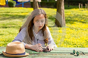 Pretty teenager girl listening to music by mobile cellpfone smartphone at the summer park