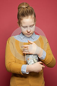 Pretty teenager girl looking at glass jar with money cash. Kids budget planning