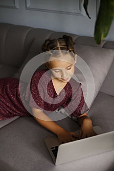 Pretty teenager girl lying on sofa in front of a laptop with. Online education distance concept