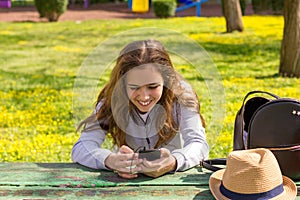 Pretty teenager girl with mobile cellpfone smartphone at the summer park