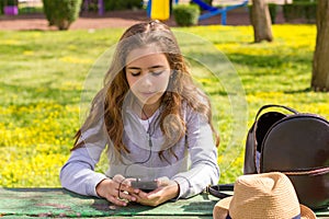 Pretty teenager girl with mobile cellpfone smartphone at the summer park