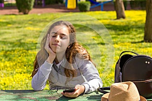 Pretty teenager girl with mobile cellpfone smartphone at the summer park