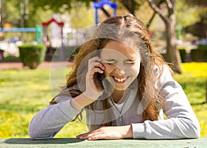 Pretty teenager girl with mobile cellpfone smartphone at the summer park