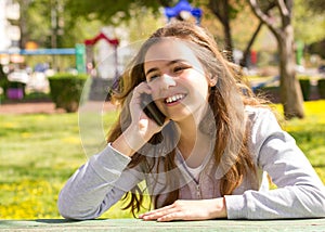 Pretty teenager girl with mobile cellpfone smartphone at the summer park