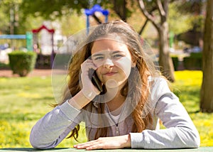 Pretty teenager girl with mobile cellpfone smartphone at the summer park