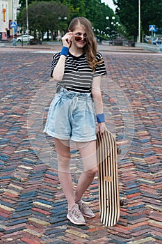 Pretty teenager girl with a skateboard in the center of a European city