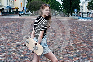 Pretty teenager girl with a skateboard in the center of a European city