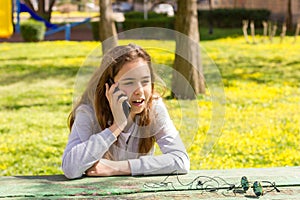 Pretty teenager girl talking by mobile cellpfone smartphone at the summer park