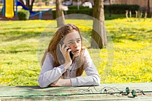 Pretty teenager girl talking by mobile cellpfone smartphone at the summer park