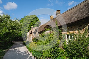 Pretty thatched roof house on a sunny day with blue sky in the Peak District, Derbyshire.  A public footpath runs past the house